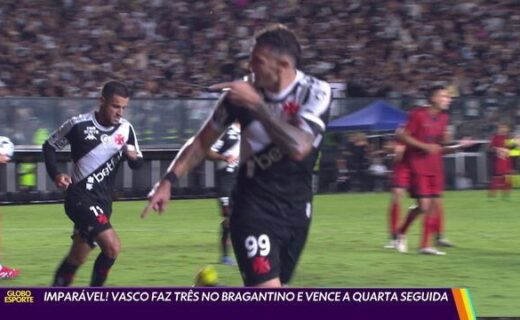 Vasco jogando no estádio com jogadores e torcida ao fundo.