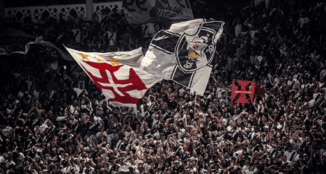 Bandeiras do Vasco sendo erguidas pela torcida.