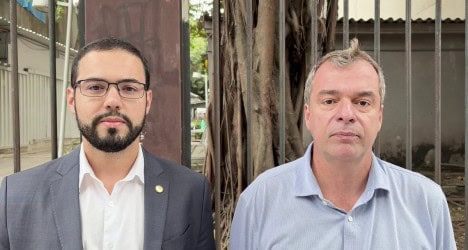 Homens em frente a barreiras de ferro e árvores.