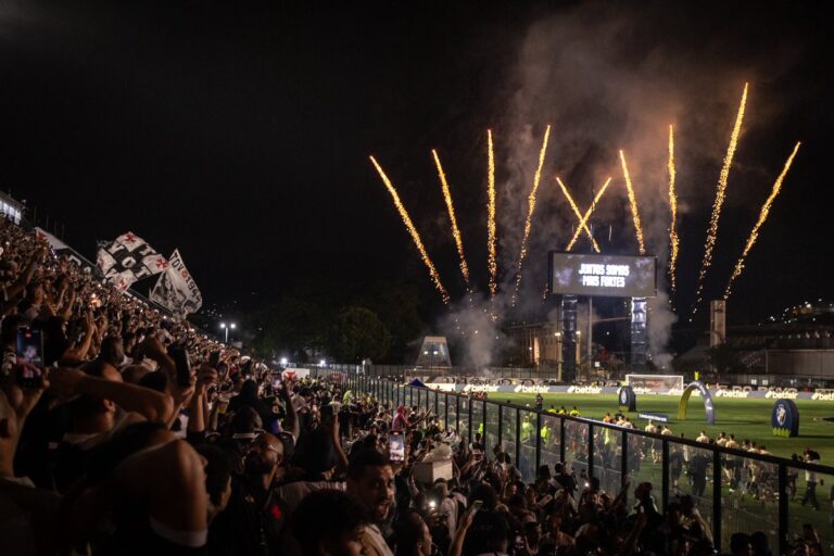 Festa no estádio com fogos de artifício e torcedores vibrando.