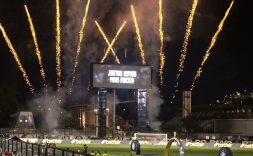 Foguetes iluminando o céu durante partida de futebol.