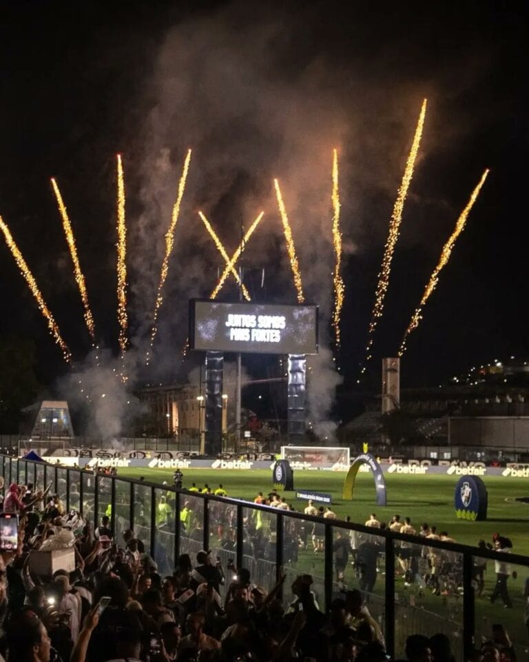 Foguetes iluminando o céu durante partida de futebol.