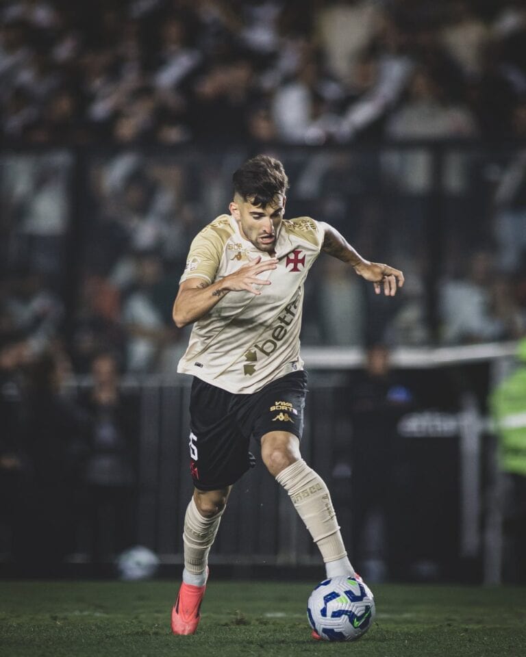 Jogador de futebol com uniforme do Vasco, controlando a bola em campo.