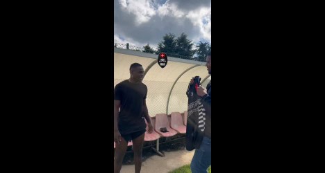 Homem recebendo camisa do Vasco em treino ao ar livre.