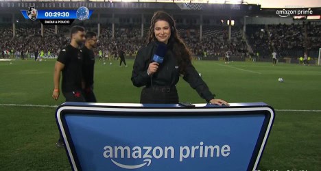 Repórter com microfone no estádio.