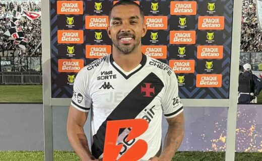 BRAZILIAN SOCCER PLAYER APPEARS WITH VASCO JERSEY AND TROPHY AT CEREMONY.