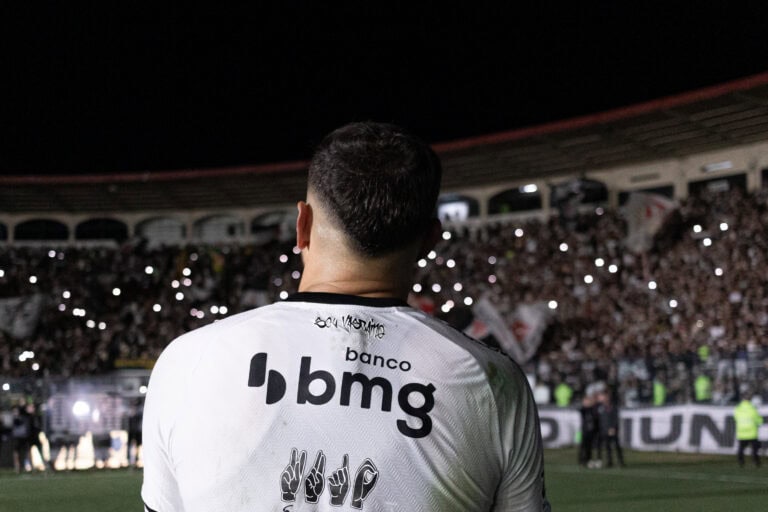 Jogador visto de costas no estádio durante a partida.