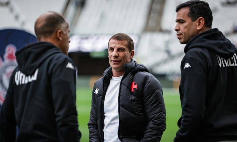 Treinador do Vasco conversando com membros da equipe no estádio.
