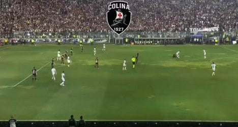 Jogadores em campo durante partida de futebol no estádio.