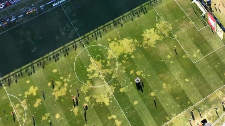 Gramado de futebol com manchas de óleo no campo.