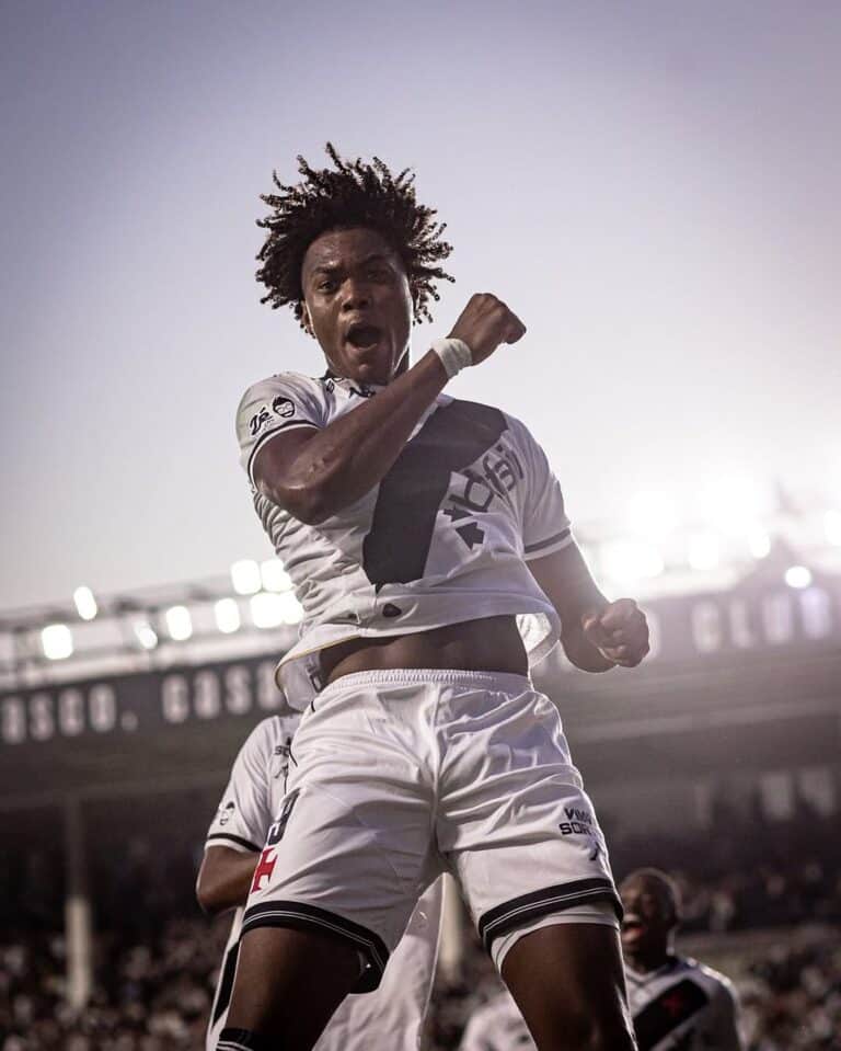 Jogador de futebol comemorando gol com expressão de vitória.