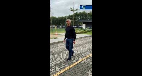 Homem caminhando na rua com céu nublado.