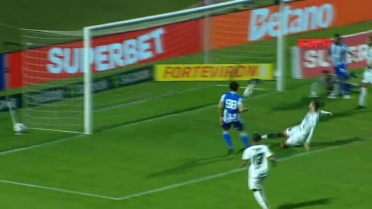 Goleiro salvando um chute na linha do gol.