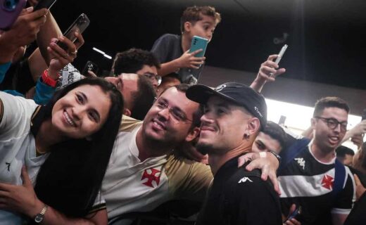 Fã sorridente com camisa do Vasco em evento com outros torcedores.