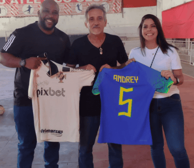 Mario Andrey e duas pessoas segurando camisas de futebol do Vasco.