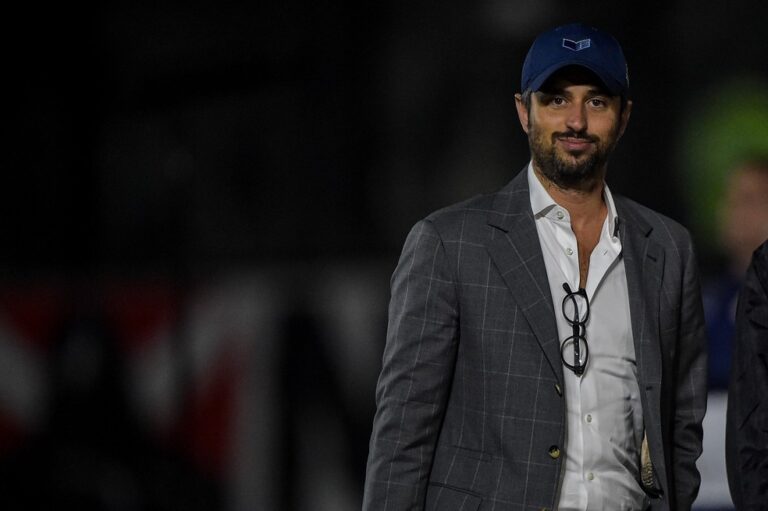 Vasco da Gama treinador em campo com traje formal e boné azul.