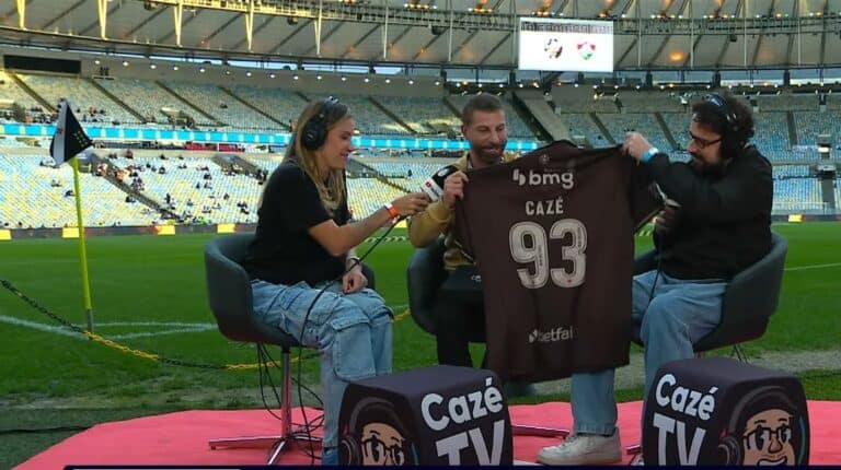 A imagem mostra três pessoas em uma entrevista no estádio do Vasco.