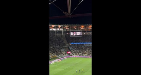 Estádio de futebol lotado durante o jogo.