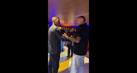 Dois homens trocando um aperto de mãos em ambiente interno.