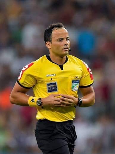 Árbitro de futebol em campo com uniforme amarelo.