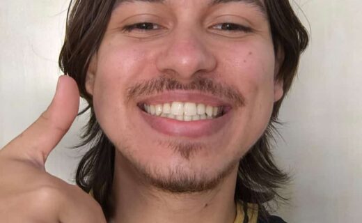 Vasco fan sorrindo com uniforme, dedo apontando, fundo liso.