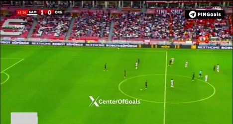 Jogadores em campo durante partida de futebol no estádio.