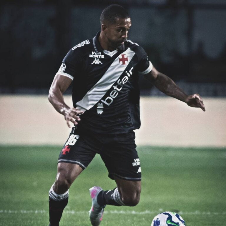 Jogador do Vasco em ação com uniforme preto; foco na camisa com logo e detalhes.