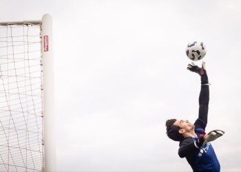 Goleiro pulando para agarrar bola.