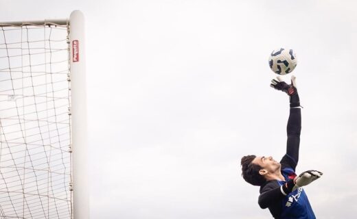 Goleiro pulando para agarrar bola.