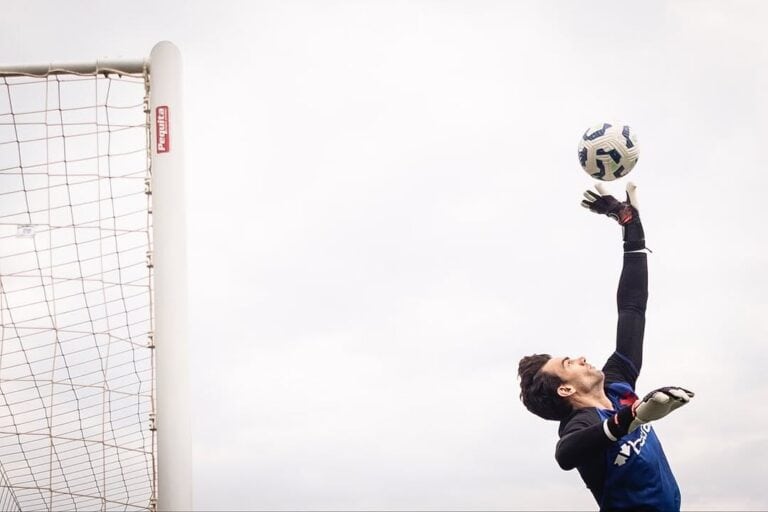 Goleiro pulando para agarrar bola.