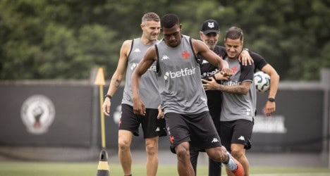 Atleta treinando com bola em campo de futebol.