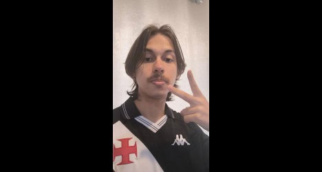 Jovem com cabelo longo e barba, fazendo gesto de paz.