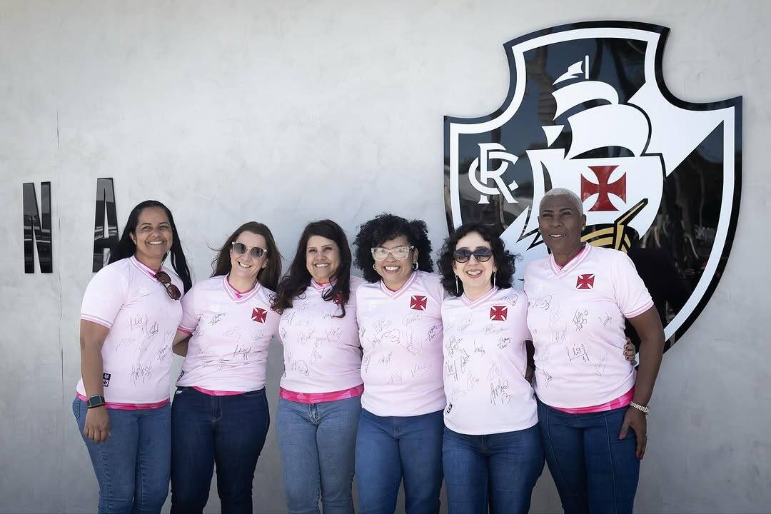 Vasco feminino com fãs e logo do clube ao fundo.