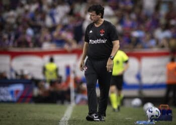 Treinador do Vasco caminhando no campo.