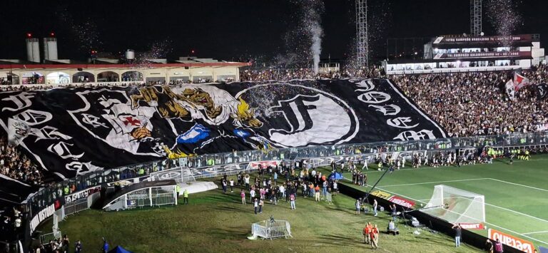 Vasco da Gama torcedor com bandeira gigante no estádio.