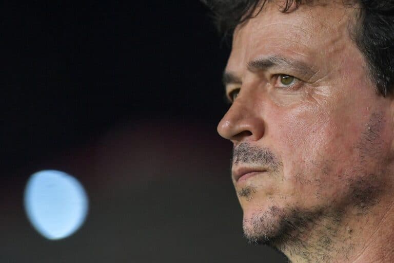 Fotografia de um homem observando atentamente, com expressão séria e focada, com fundo escuro.