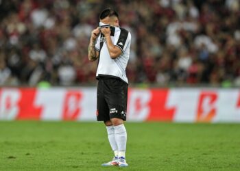 Chorando e cobrindo o rosto com a camisa.