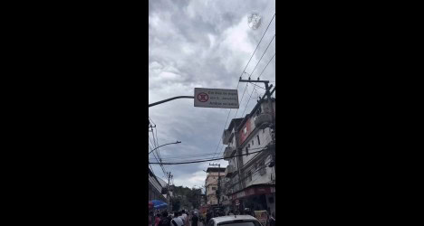 Táxi parado na rua com prédio ao fundo e avisos de trânsito.