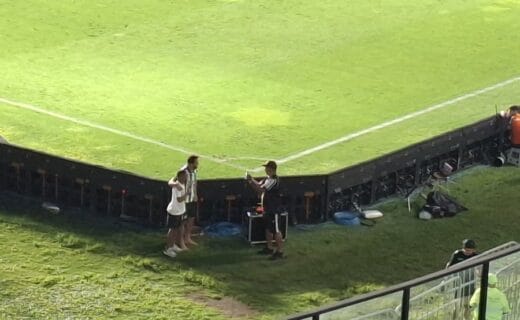 Estádio de futebol com técnicos e equipe de suporte.