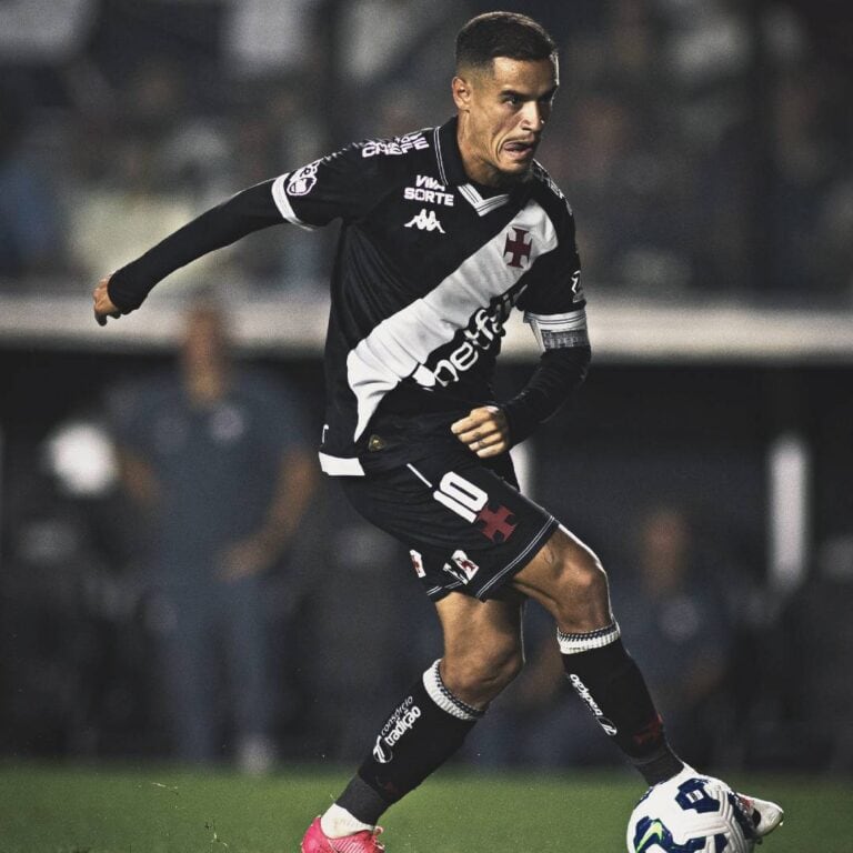 Vasco jogando com uniforme preto e branco, jogador em ação com a bola.