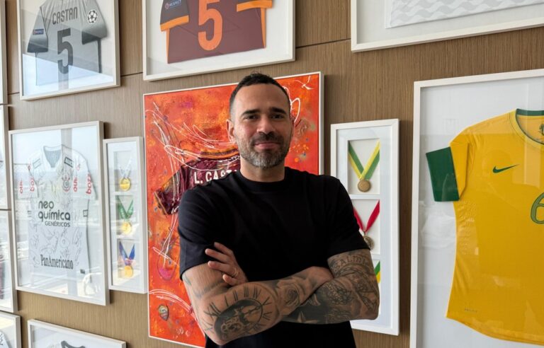 Vestido preto com braços cruzados em exibição de troféus e camisas de futebol.