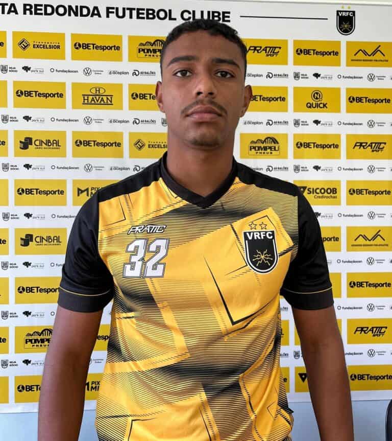 Jogador com uniforme do Vasco em fundo de patrocinadores.