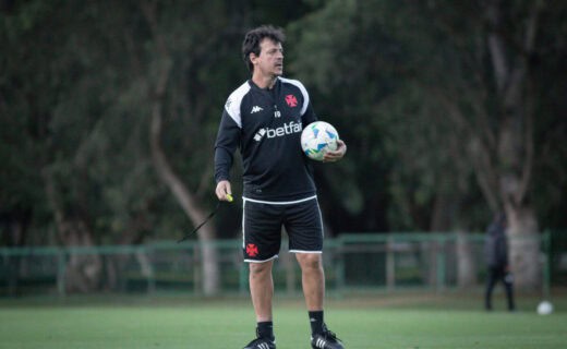 Treinador com bola de futebol no campo.