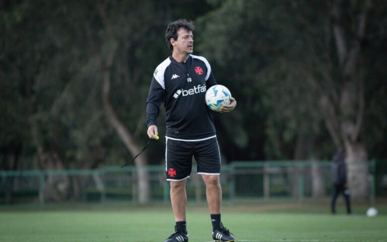 Treinador com bola de futebol no campo.