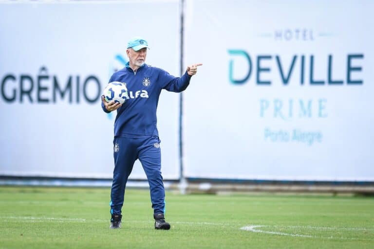 Treinador de futebol com bola em campo.