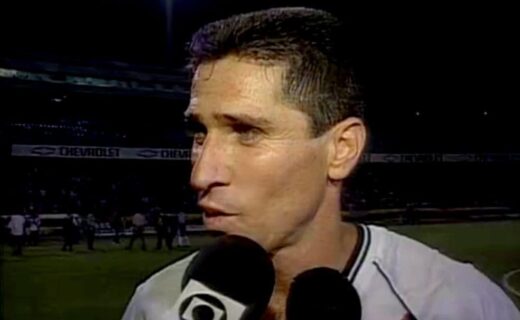 Jogador de futebol com cabelo curto e camisa branca.