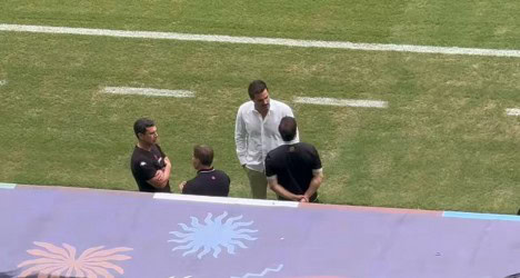 Homens conversando no campo de futebol.