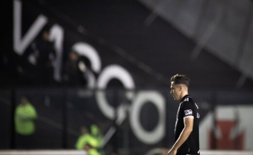 Jogador do Vasco pensativo em campo à noite.