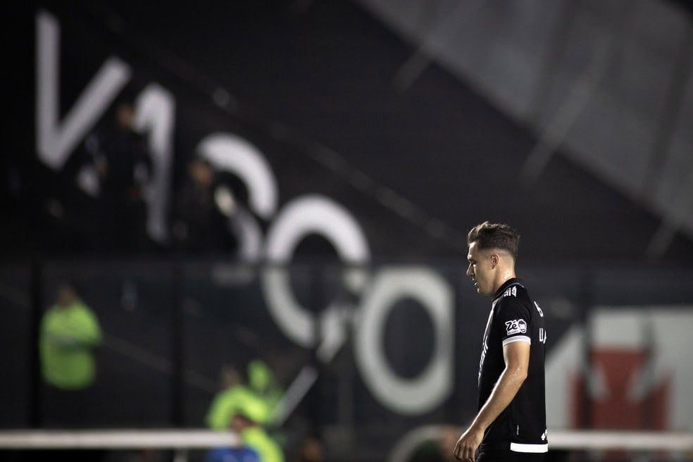 Jogador do Vasco pensativo em campo à noite.