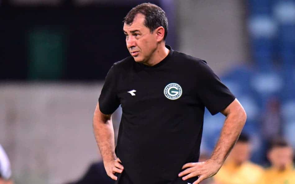 Treinador do Vasco em uniforme preto, com mãos na cintura, durante partida.